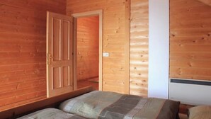 Une pièce de cabane en bois avec un lit, une porte et un mur blanc.