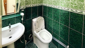 Un baño con baldosas de mármol verde, un lavamanos blanco y un inodoro.
