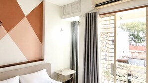Habitación de hotel con cama, una mesita, una silla y un balc ón con vistas.