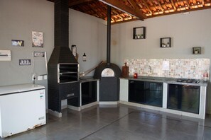 Eine Küche mit eingebautem Holzofen, einem Kühlschrank und einer gefliesten Spritzschutzwand.
