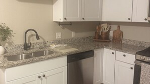 A kitchen with white cabinets, a stainless steel sink, a dishwasher, and a stove. - Cozy & Fancy 3BR Cottage Near Historic Downtown McKinney - Family Mid-Term Ready (McKinney)