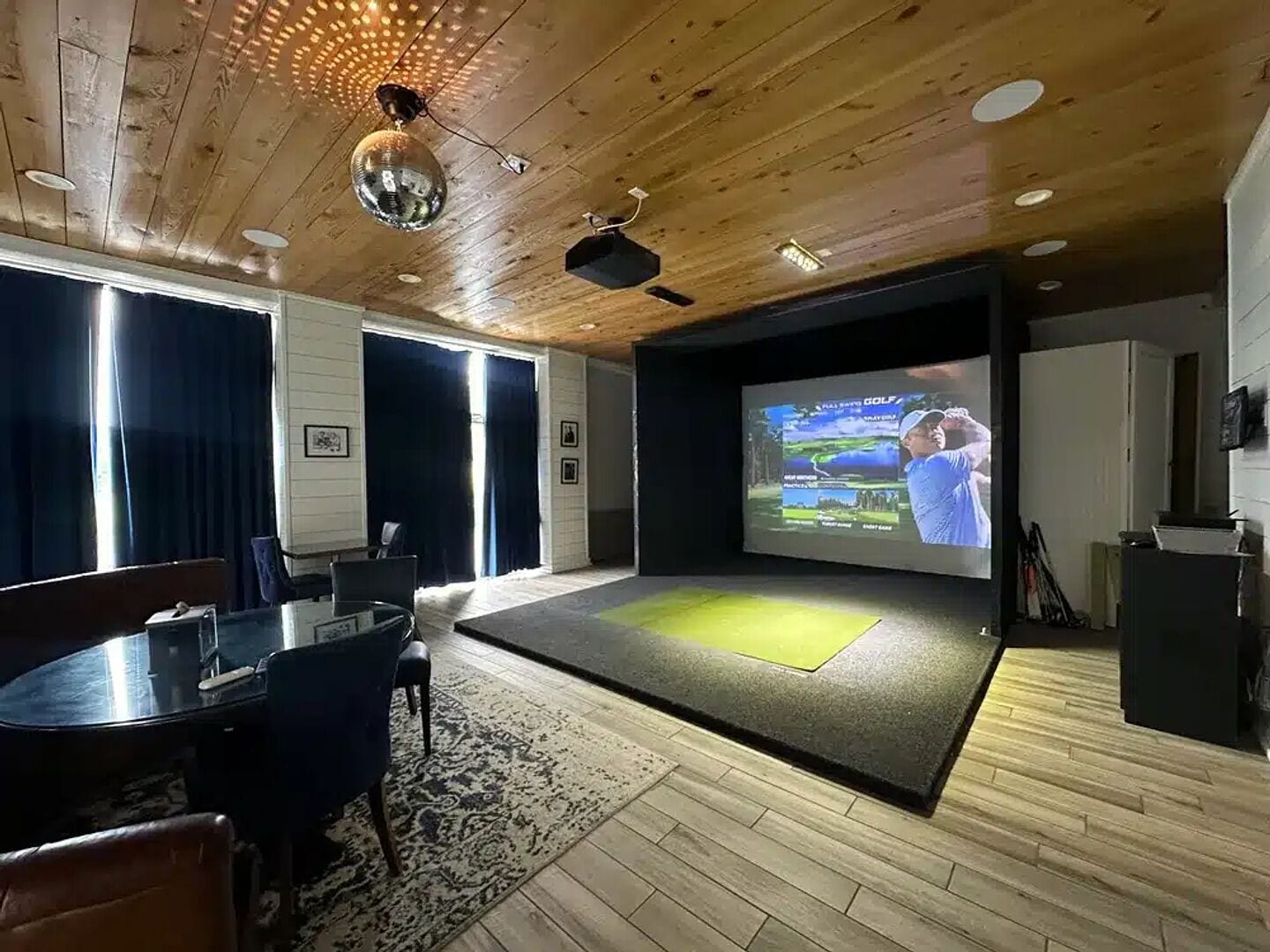 A home theater room with a large screen, wooden ceiling, and a cozy seating area.