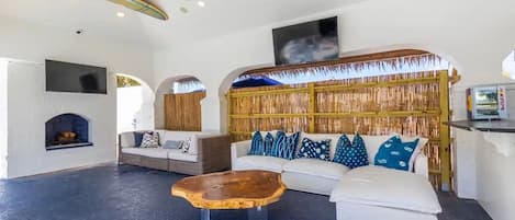 A spacious living area with a white sofa, a wooden coffee table, and a bamboo wall.