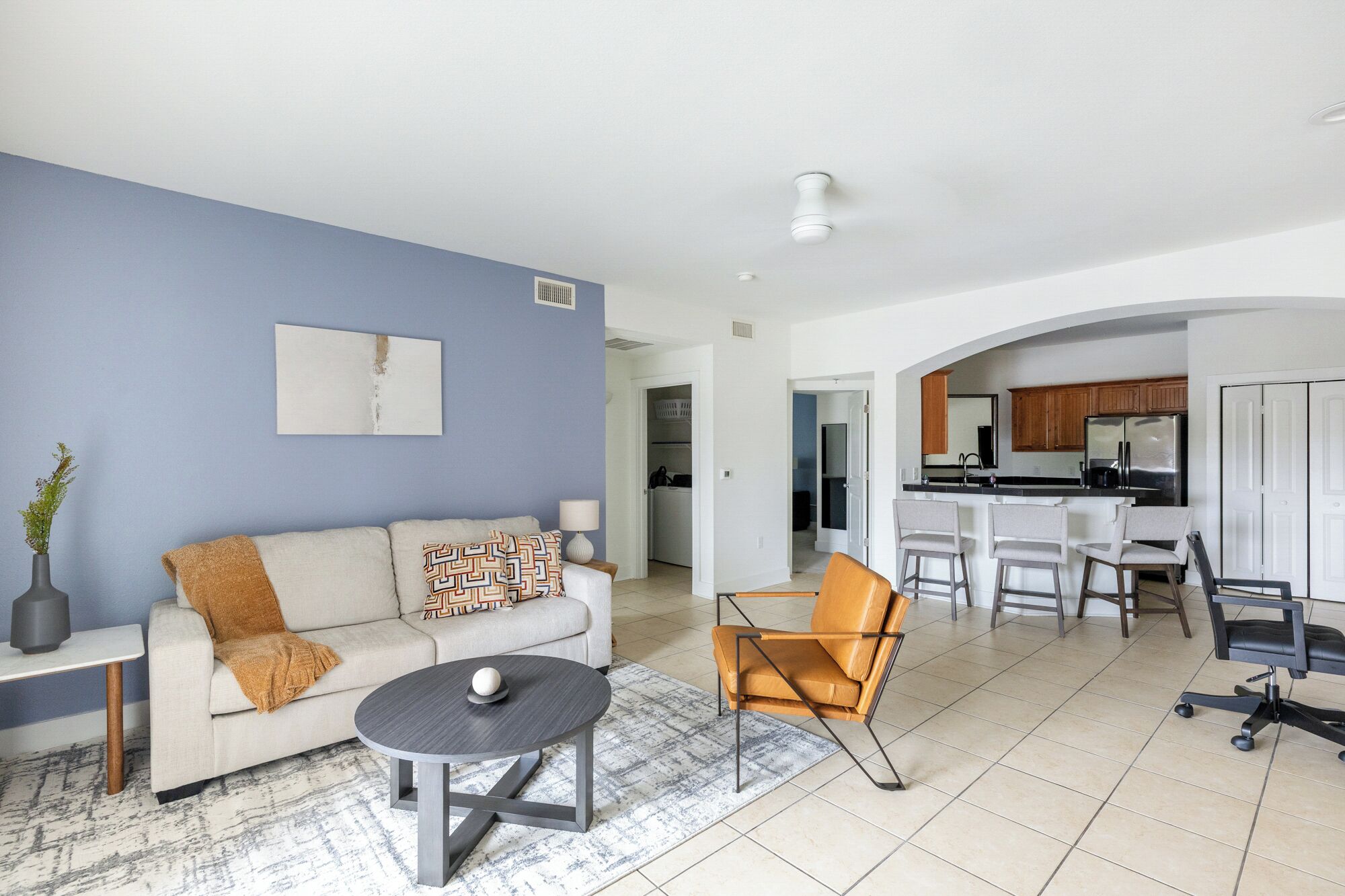 A modern living room with a sofa, coffee table, and a dining area with bar stools.