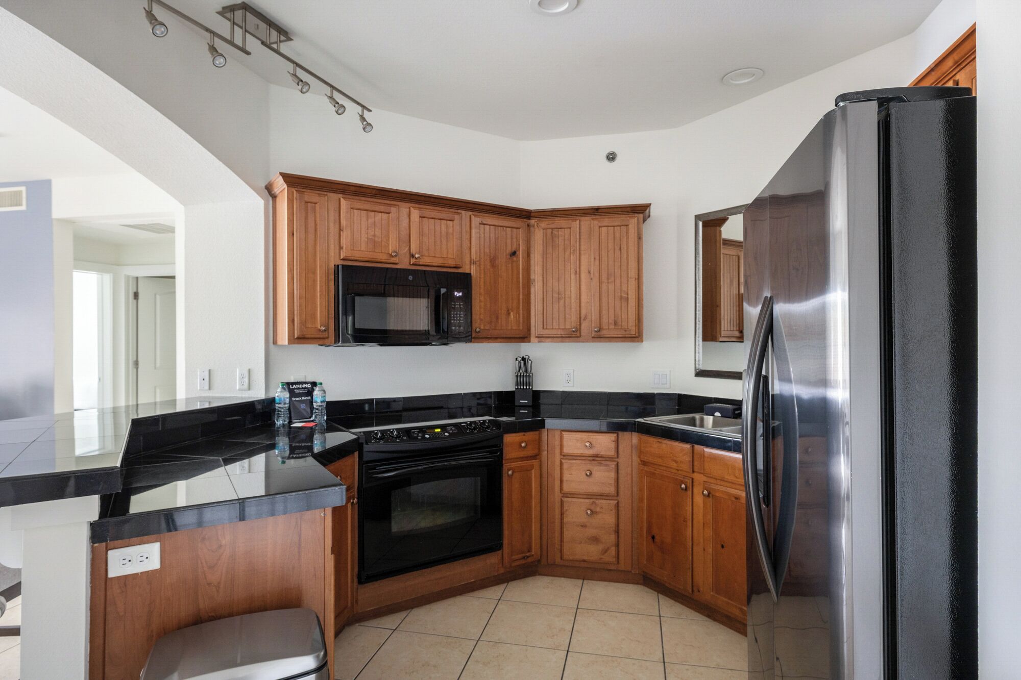 A modern kitchen with wooden cabinets, a stainless steel refrigerator, a microwave, and a stove.