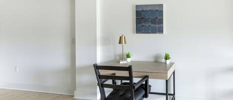A modern office space with a wooden desk, black office chair, and a small potted plant.