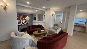 A modern living room with red and grey sofas, a coffee table, and a TV on a wooden console. - Landing Apartments near Rivergate Park Area (Cleveland)