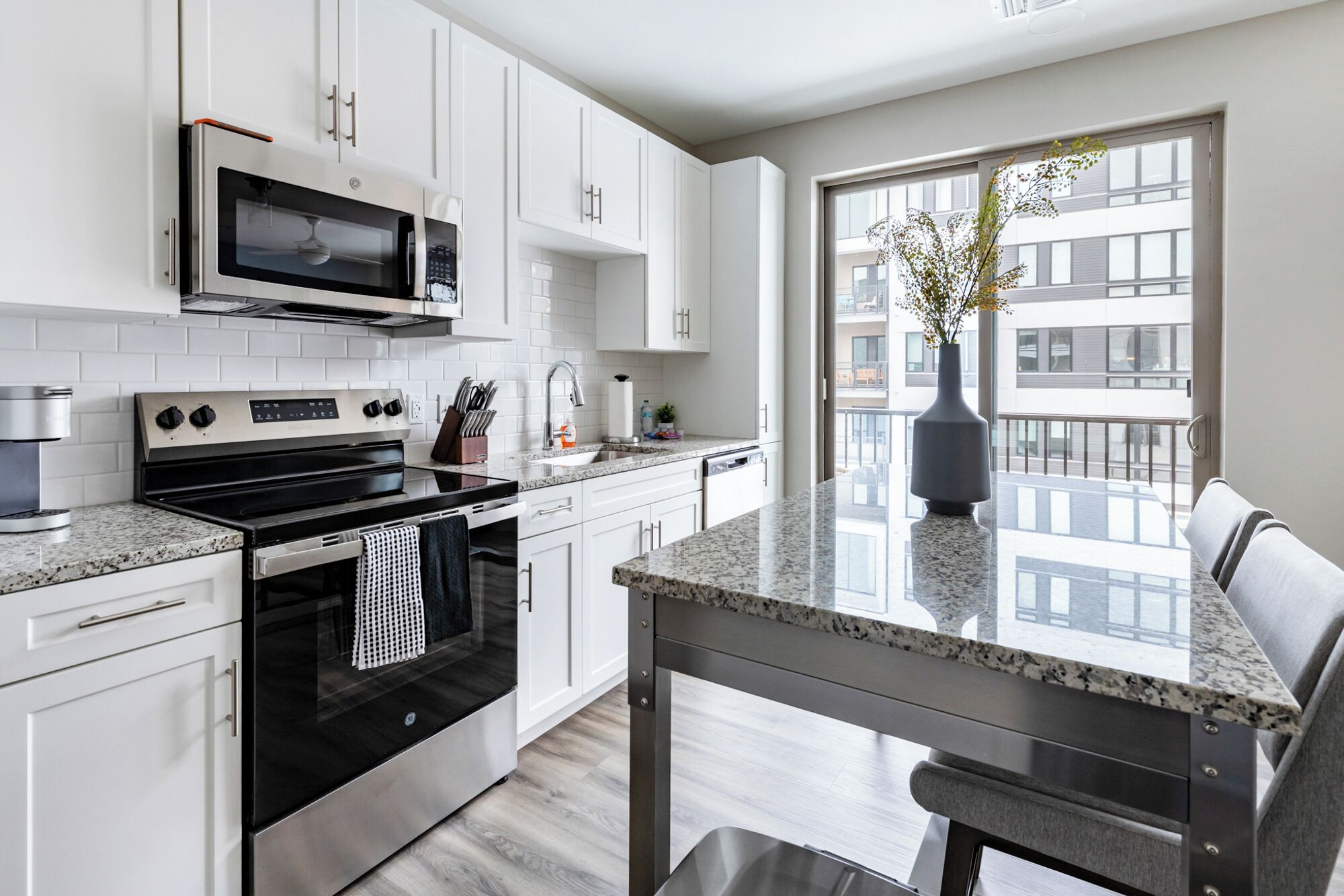 A modern kitchen with white cabinets, stainless steel appliances, and a granite countertop.