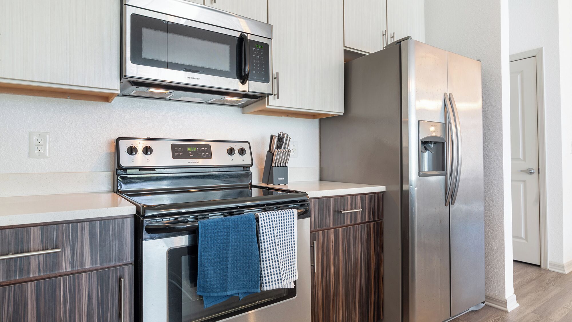 A modern kitchen with a stainless steel refrigerator, a microwave, and an oven.