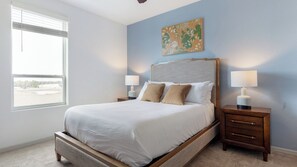 Une chambre à coucher avec un lit, deux tables de chevet, une fenêtre et un tableau au mur.