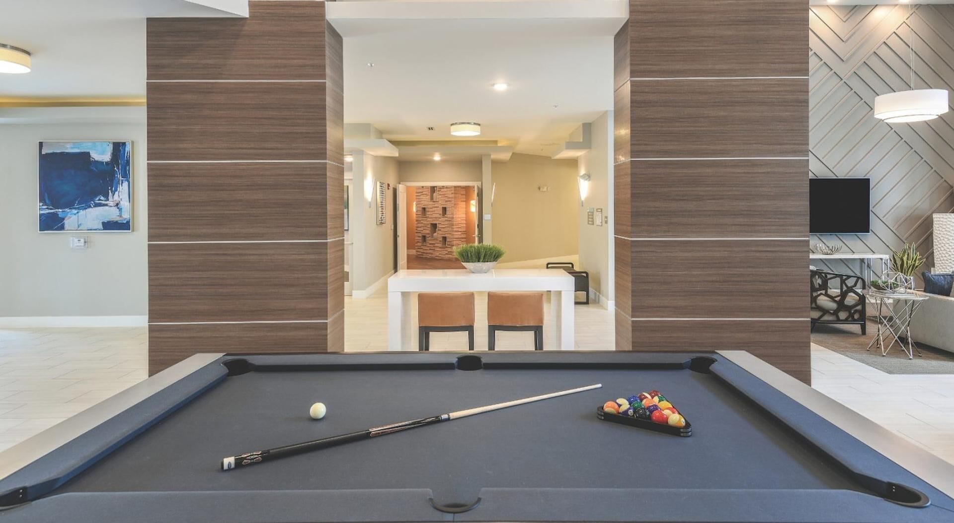 A pool table with a cue stick and balls, a dining area with a table and chairs, and a modern living room with a TV and decorative items.