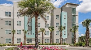 Un immeuble moderne à plusieurs étages, avec une variété de styles de fenêtres et un palmier au centre.