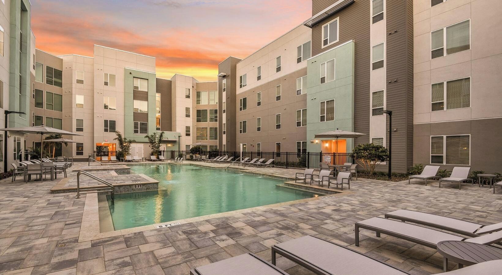 A hotel pool area with multiple lounge chairs and a swimming pool.