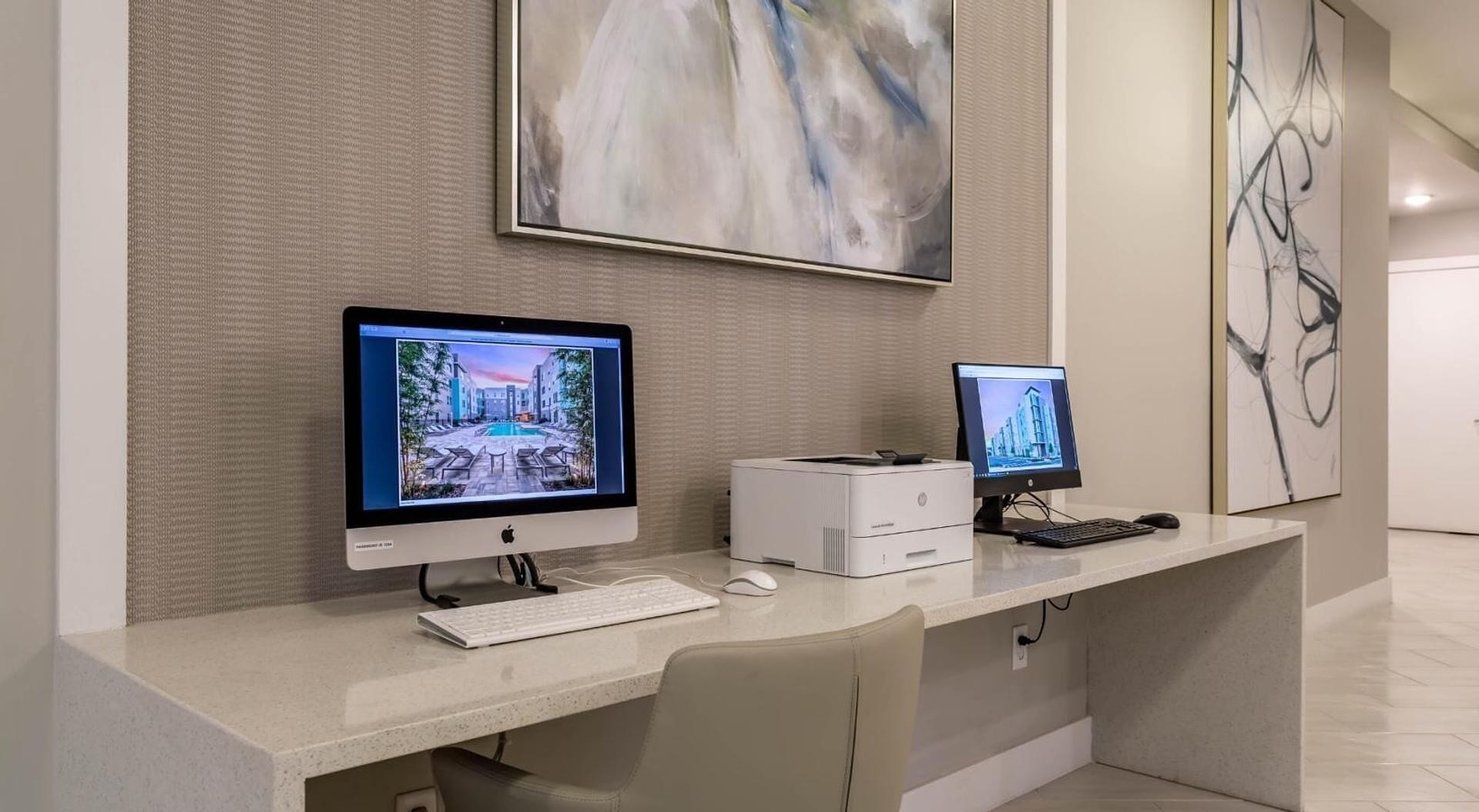 A modern office desk with two monitors, a keyboard, a mouse, and a printer.