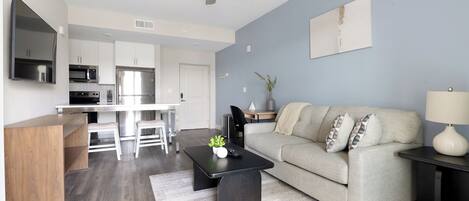 A modern living room with a sofa, coffee table, and a TV mounted on the wall.