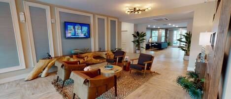 A spacious living room with a large wooden coffee table, comfortable seating, and a television mounted on the wall.