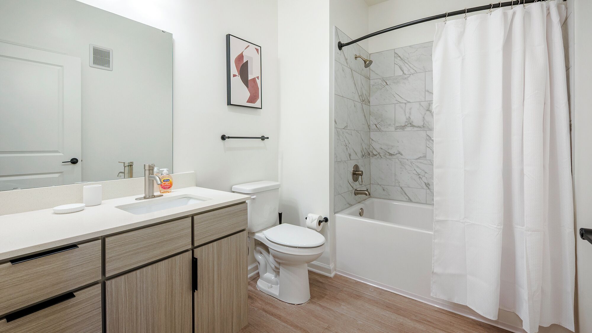 Un baño moderno con lavamanos, inodoro y bañera blancos.