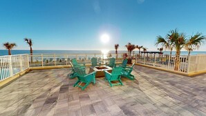 Eine Terrasse mit Feuerstelle, Sitzgelegenheiten im Freien und Meerblick.
