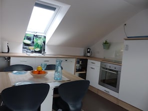 Una cucina moderna con un lucernario, un tavolo da pranzo con sedie, un frigorifero e una macchina per il caffè.