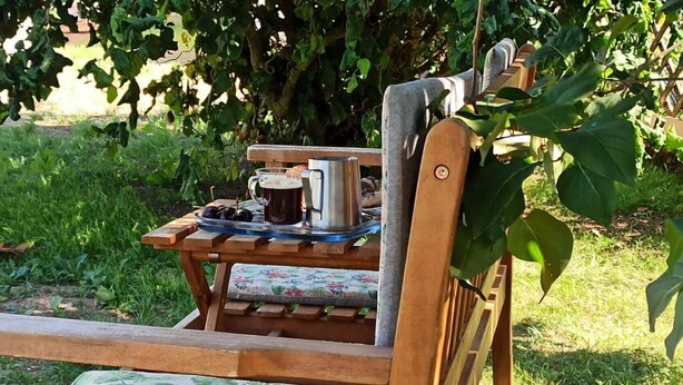 A wooden bench with a table, a metal pitcher, and a glass mug. - Alb-Biosphere Holiday Apartment (Ingstetten)