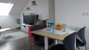 A modern living space with a dining area, a TV, and a plant. - Alb-Biosphere Holiday Apartment (Ingstetten)