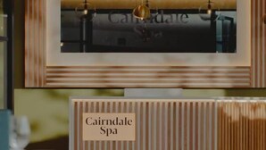 A reception desk with a sign reading 'Cairndale Spa' and a framed mirror above it. - Cairndale Hotel & Spa (Dumfries)