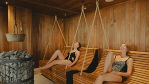 Two wooden benches with ropes, a stone pillar, and a hanging bucket in a wooden room. - Cairndale Hotel & Spa (Dumfries)