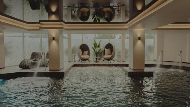 A spa area with a hot tub, two wicker chairs, and a small table with a plant. - Cairndale Hotel & Spa (Dumfries)