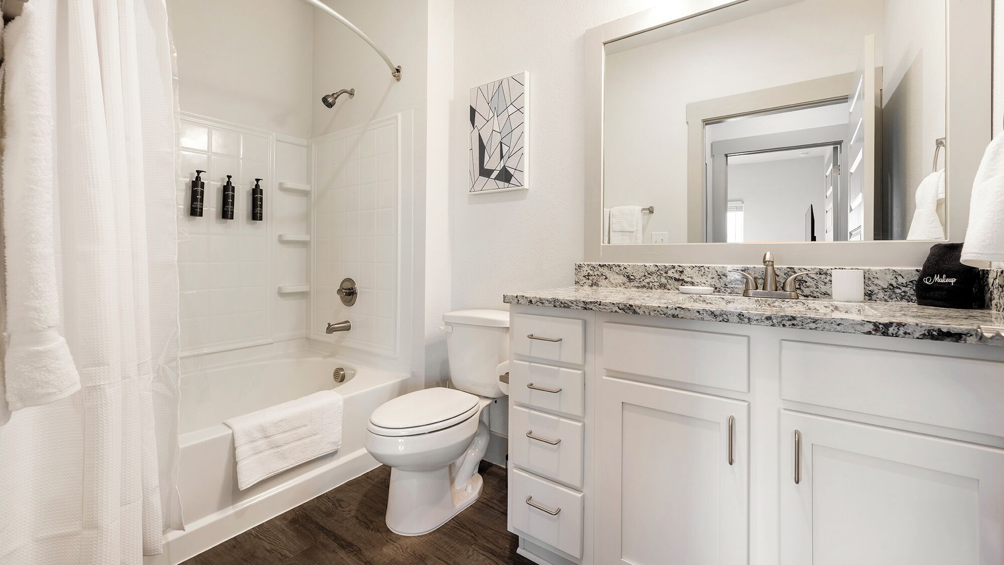 A modern bathroom with a bathtub, toilet, and vanity.
