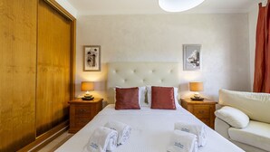 Ein Hotelzimmer mit einem großen Bett, zwei Nachttischen mit Lampen, einem weißen Kopfteil und einem Holzschrank.