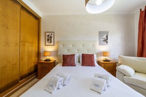 A hotel room with a large bed, two bedside tables with lamps, a white headboard, and a wooden wardrobe. - Villa Moises  - an excellent property 500 mts from the famous Falésia beach (Albufeira)