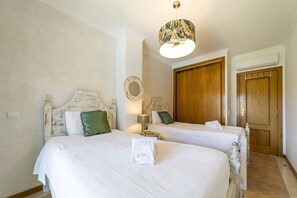 A hotel room with two beds, a wooden wardrobe, a mirror, and a ceiling fan. - Villa Moises  - an excellent property 500 mts from the famous Falésia beach (Albufeira)