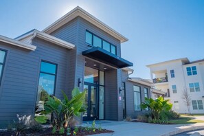 A modern building with a flat roof, large windows, and a small balcony.