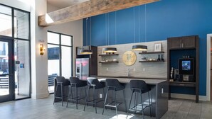A modern kitchen with a bar area, large windows, and a blue accent wall. - Landing Apartments Near North Okaloosa Medical Center (Crestview)