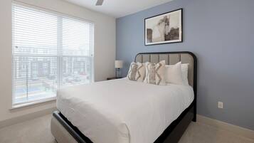 A bedroom with a bed, a nightstand, a lamp, and a window with blinds.