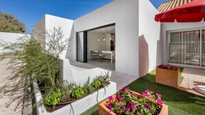 A modern house with a patio, a dining area, and a red umbrella. - Villa AL Fresco, a cosy villa with fabulous exterior areas & private pool (Guia)