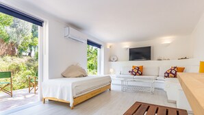 A modern bedroom with a bed, a sofa, and a TV. There is a window with a view of greenery outside. - Villa AL Fresco, a cosy villa with fabulous exterior areas & private pool (Guia)