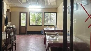 Une pièce dotée d’un ventilateur de plafond, d’une grande fenêtre et d’une table avec des chaises.