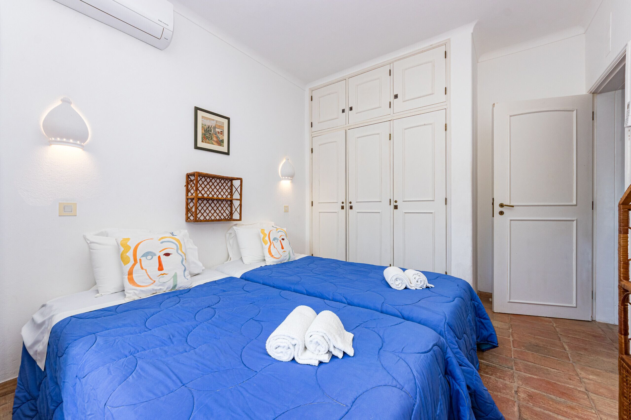 A hotel room with two beds, a wardrobe, and a door.