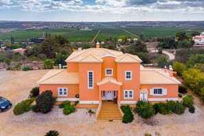 A large, two-story house with a tiled roof, surrounded by a gravel driveway and lush greenery. - Villa da Horta, a beautiful extensive villa in a peaceful location (Alcantarilha)