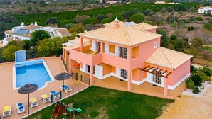 Ein großes, zweistöckiges Haus mit Swimmingpool, Sitzgelegenheiten im Freien und einem Spielplatz.