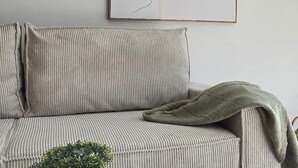 Una stanza con un divano, una coperta verde e un quadro astratto appeso al muro.