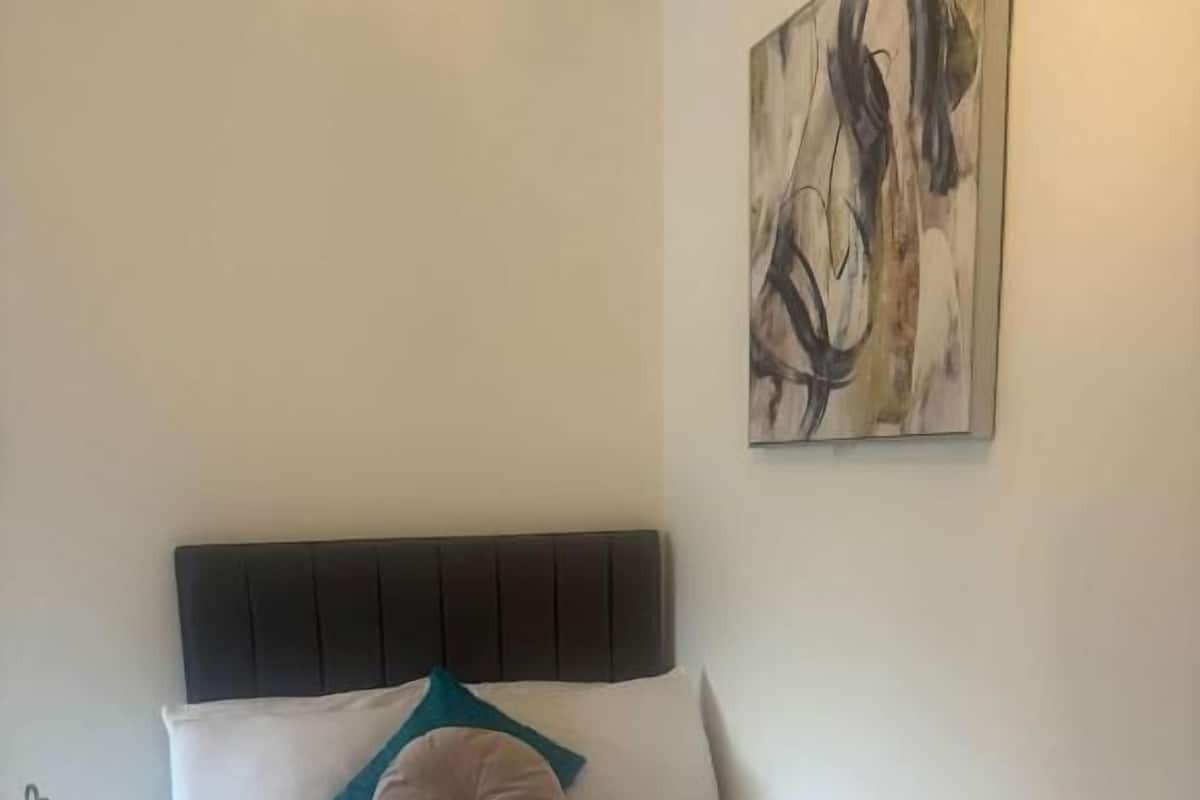 Une chambre à coucher avec un lit, une table de chevet et un tableau accroché au mur.