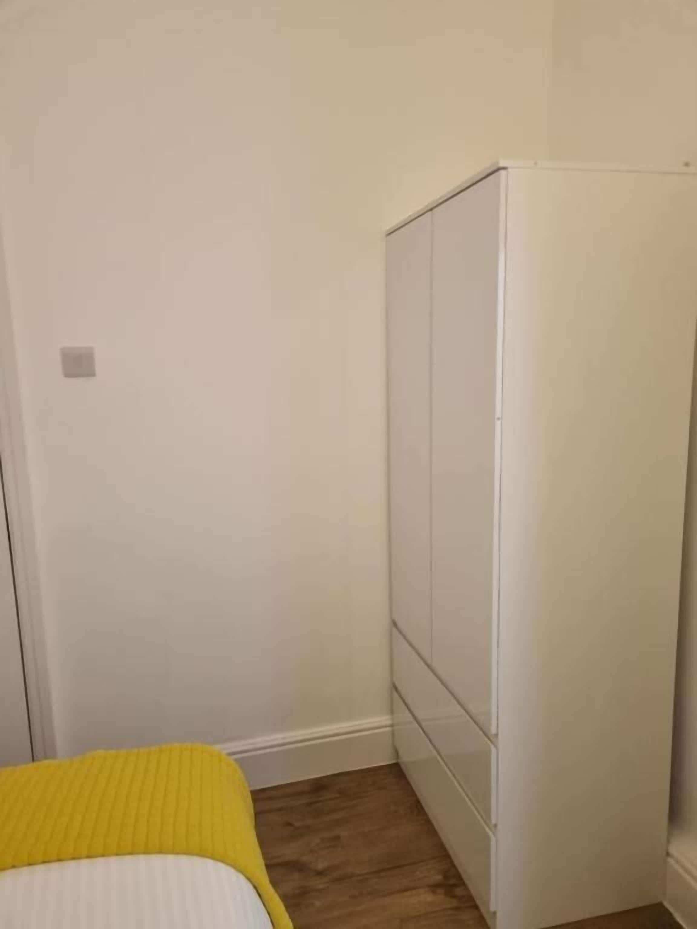 A room with a bed, a wardrobe, and a wooden floor.