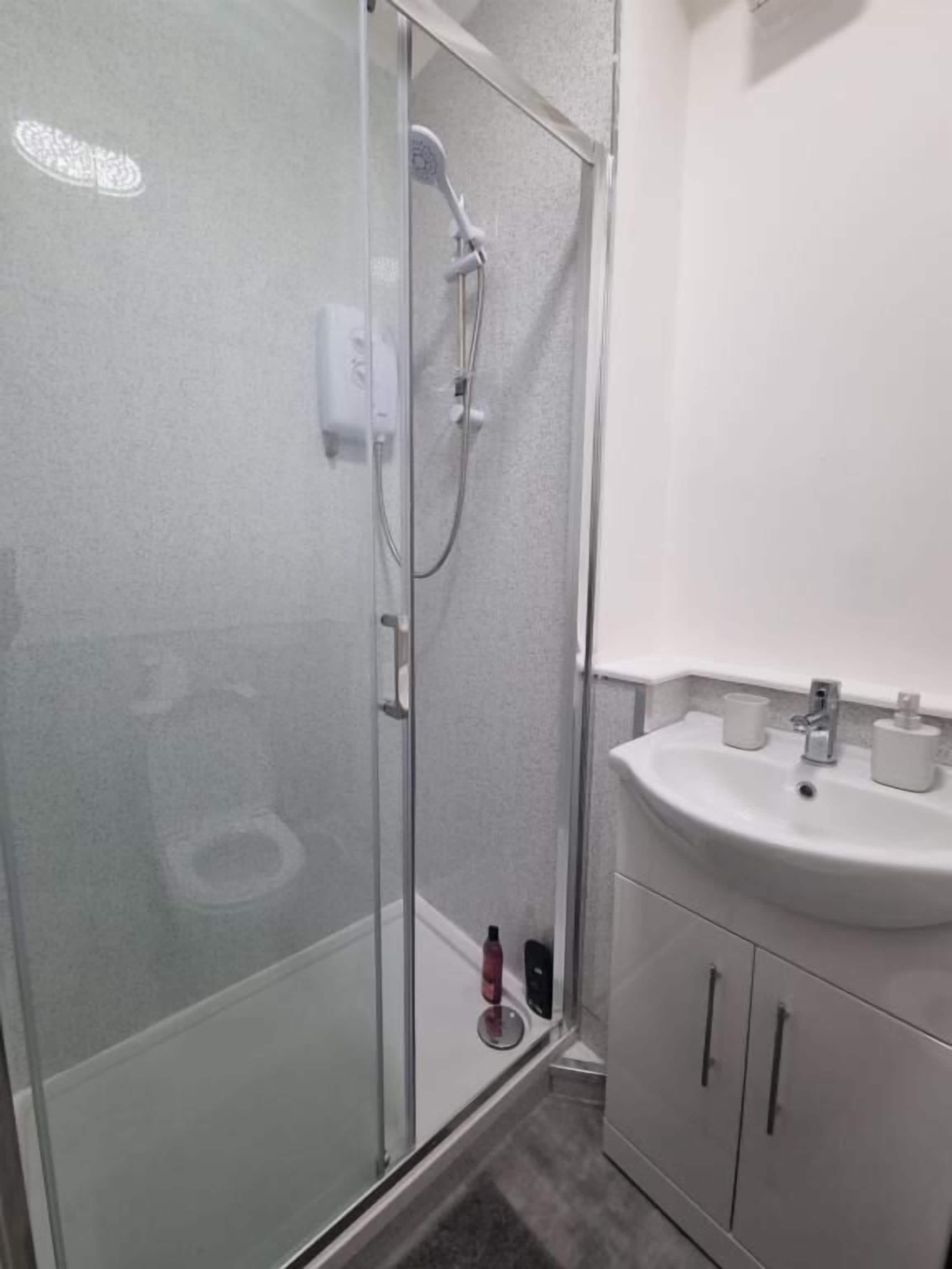 A bathroom with a glass-enclosed shower, a white sink, and a mirror above the sink.