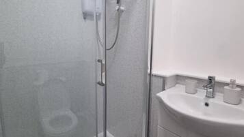 A bathroom with a glass-enclosed shower, a white sink, and a mirror above the sink.