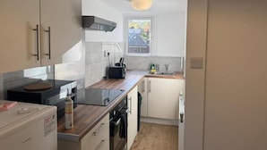 Una cocina moderna con armarios blancos, encimera de madera, horno empotrado y ventana que proporciona luz natural.