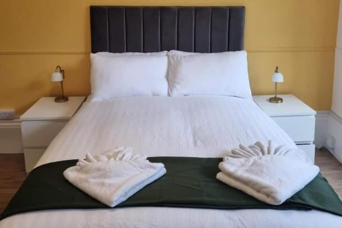Une chambre d’hôtel avec un lit, deux tables de chevet et deux lampes.