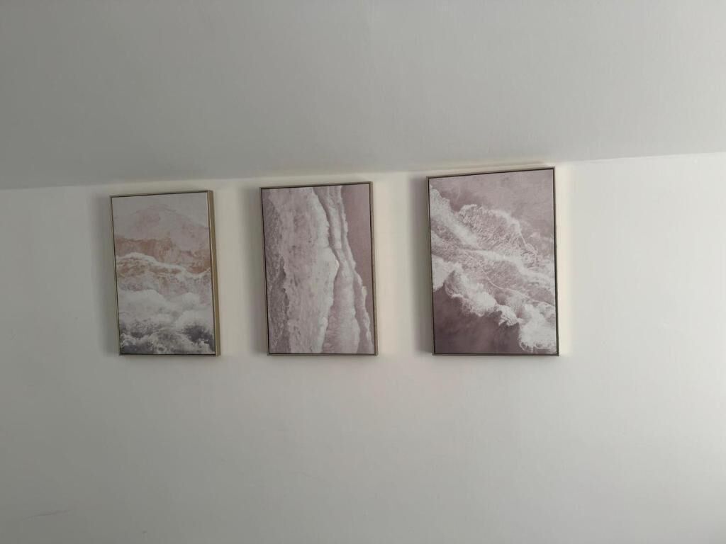 Three framed abstract paintings on a plain wall.