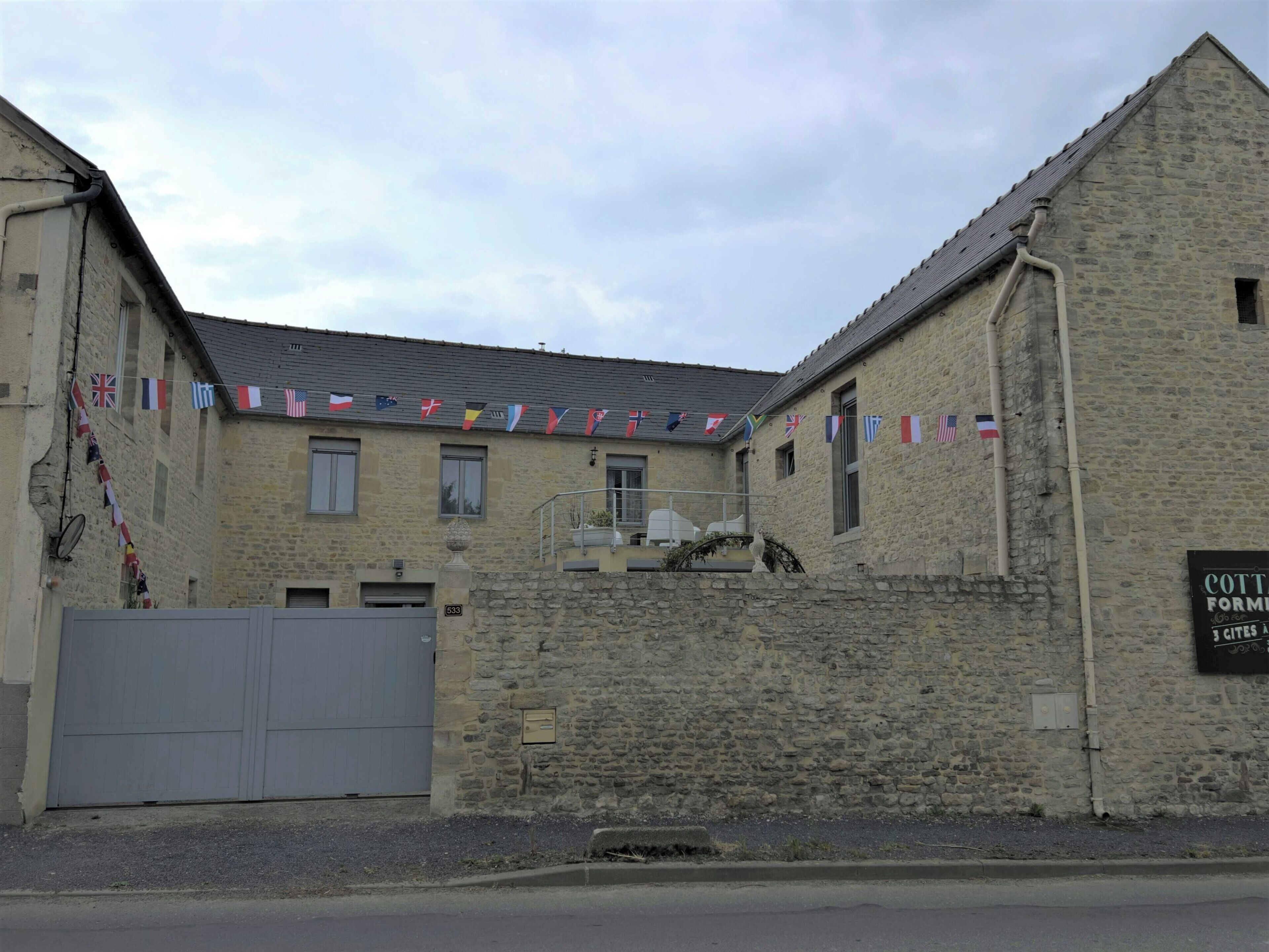 Een stenen gebouw met een bord waarop staat: COTTAGE FORMATURE 13 CITES.
